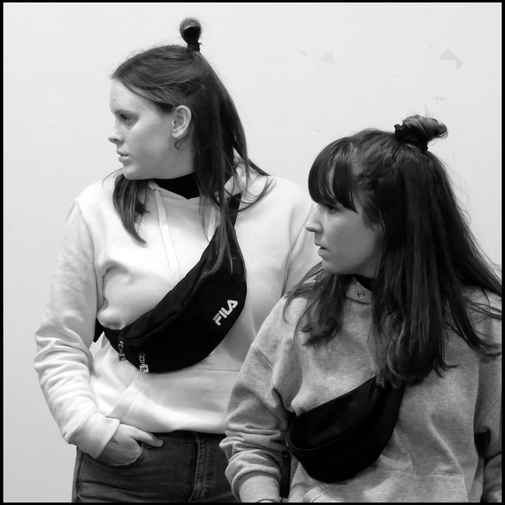 Twee personen, gekleed in sweatshirts en heuptassen, met hun haar in een staart.