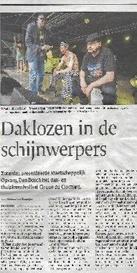 Drie mannen op een podium onder fel licht. Krantenartikel over daklozen.