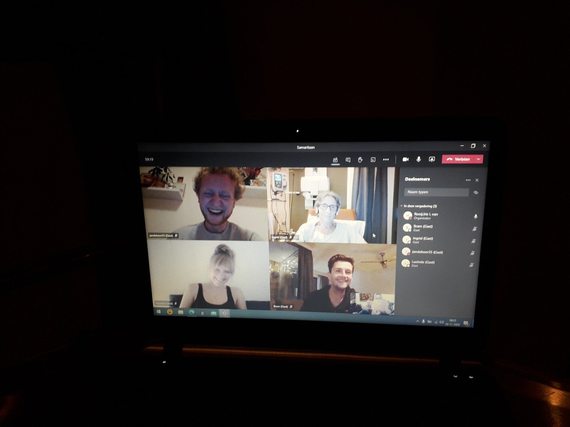 Op het laptopscherm is een videogesprek te zien met vier mensen. Ze glimlachen en nemen actief deel aan het gesprek.