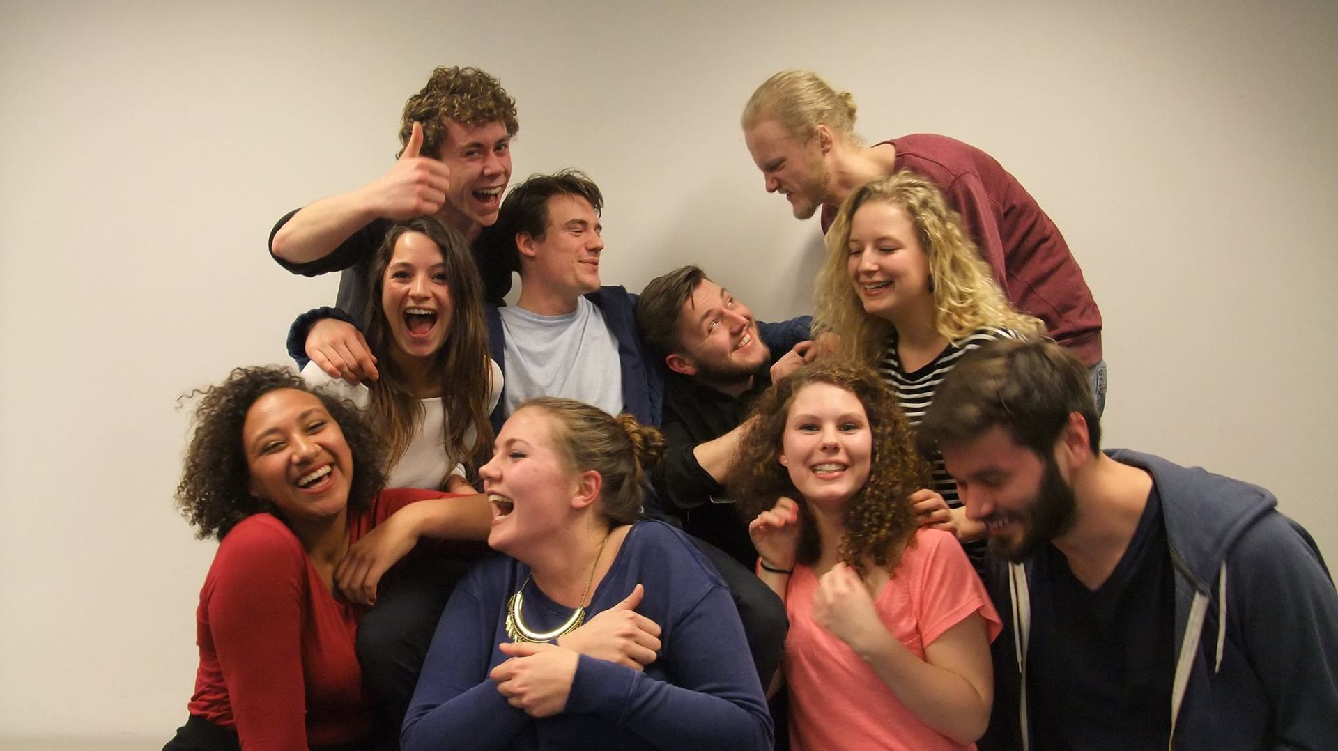Een groep mensen lacht en glimlacht samen tegen een witte achtergrond.