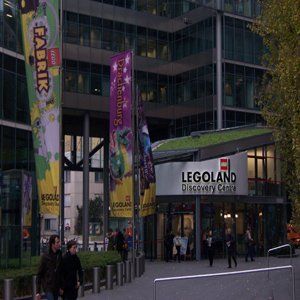 Eine Gruppe von Leuten läuft vor einem Gebäude mit der Aufschrift „Legoland Discovery Center“.