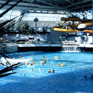 Menschen schwimmen in einem großen Pool mit einer Wasserrutsche im Hintergrund
