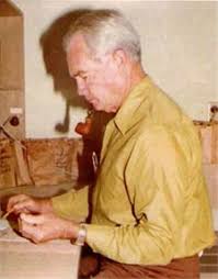 A man in a yellow shirt is sitting at a table.