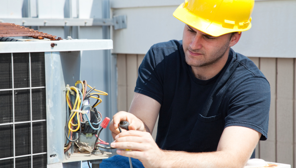 hvac tech repairing heat pump