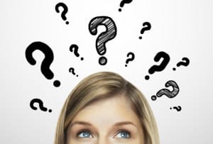 A woman is looking up at a bunch of question marks flying around her head.
