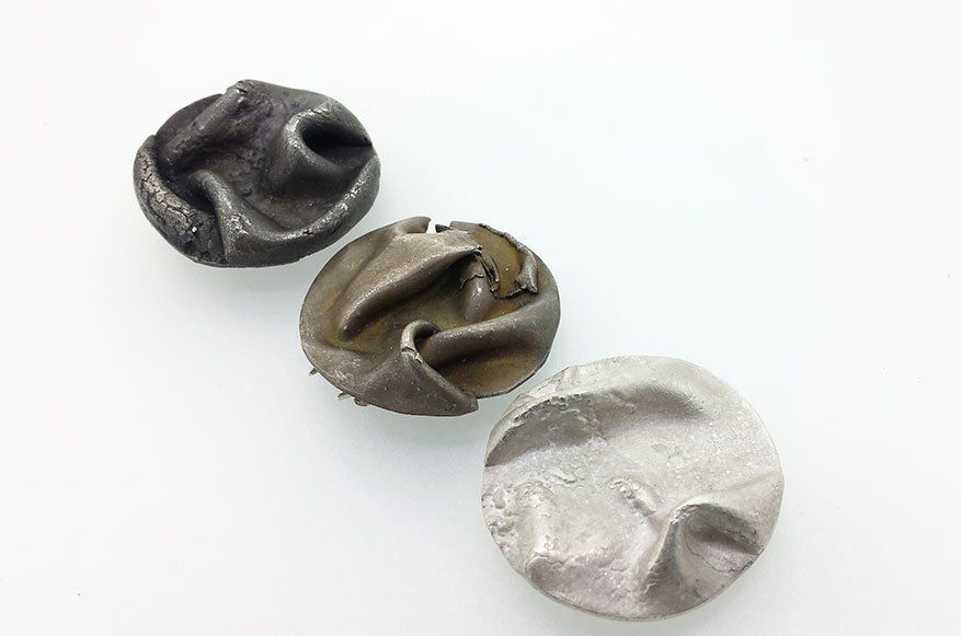 A collection of textured/folded fine silver circular brooches with oxidised and unoxidised finishes