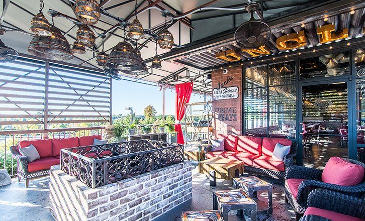 a patio with a fire pit , couch , chairs and tables at uncle jacks meathouse duluth