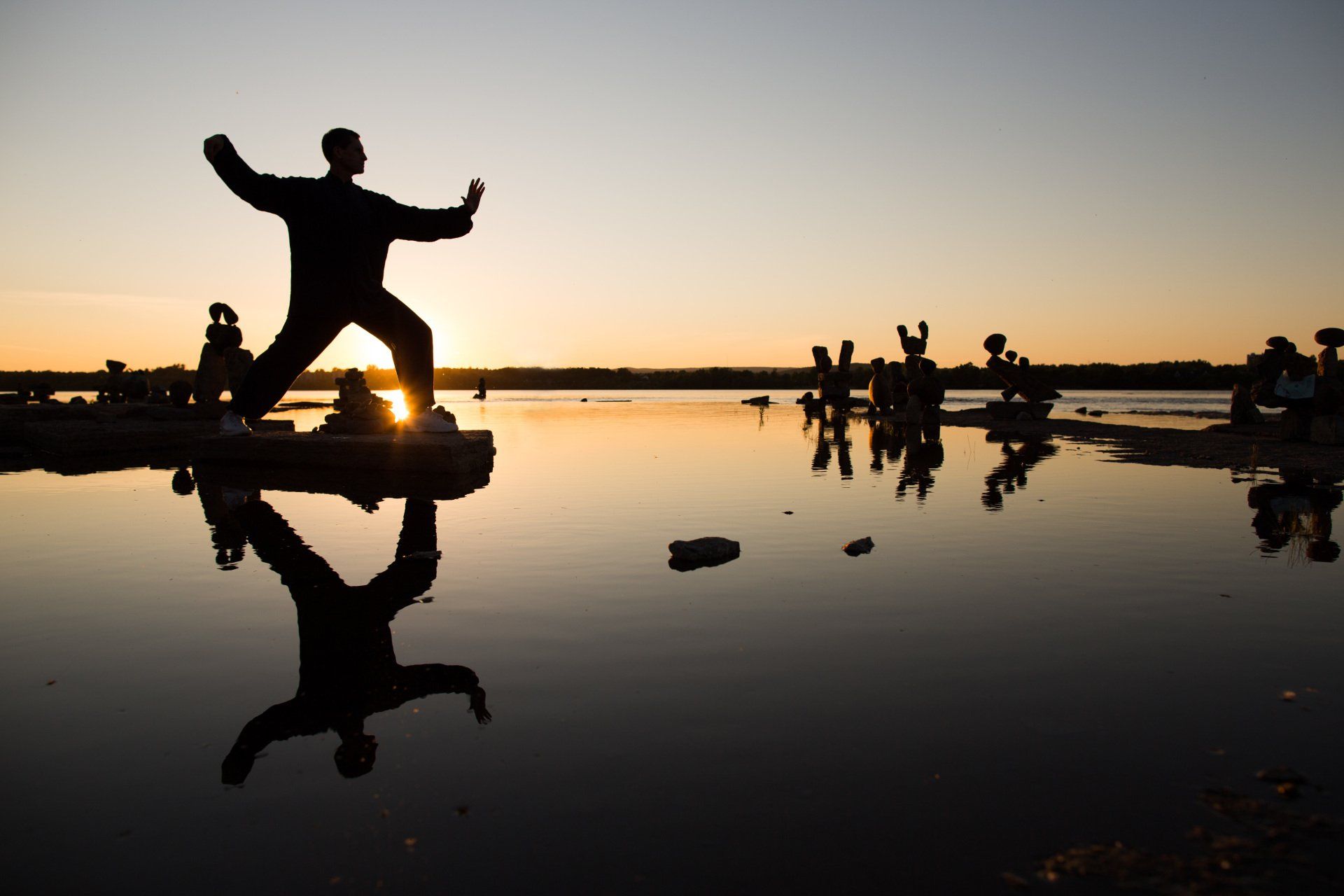 Tai Chi Single Whip posture on rocks in the water.