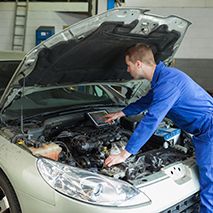 mechanic working on computer system under vehicle hood