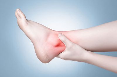 Woman Massaging Her Painful Ankle — Glenview, IL — Dr. Ron Riegelhaupt and Associates Woman Massaging Her Painful Ankle — Glenview, IL — Dr. Ron Riegelhaupt and Associates