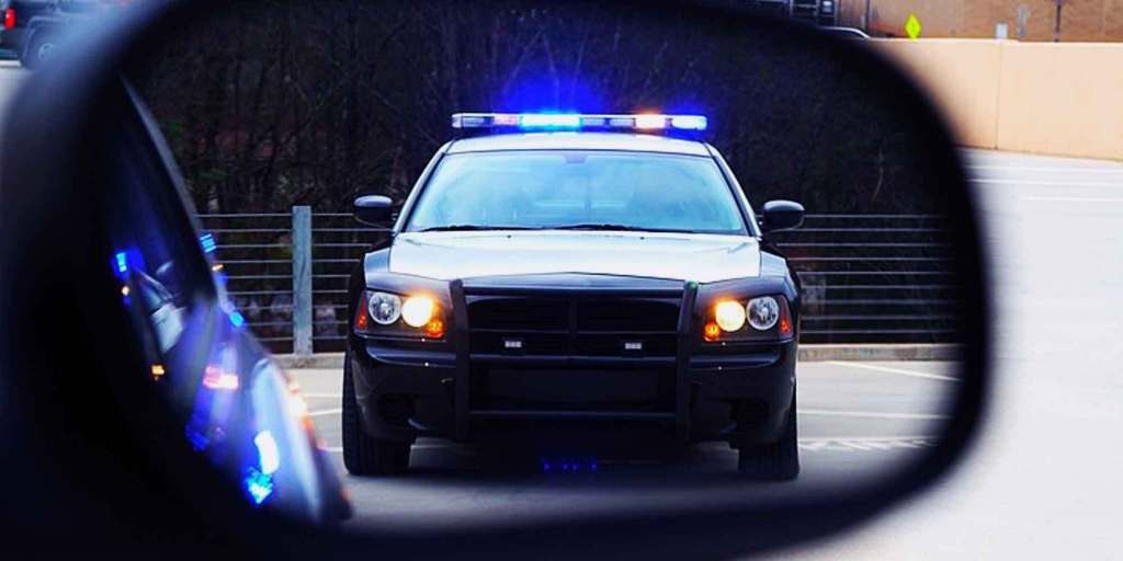 Person driving a car with beer bottle in hand