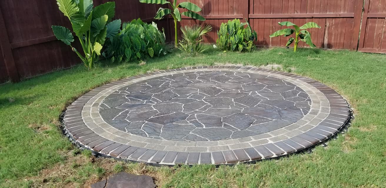 circular brick and concrete patio surrounded by grass and plants