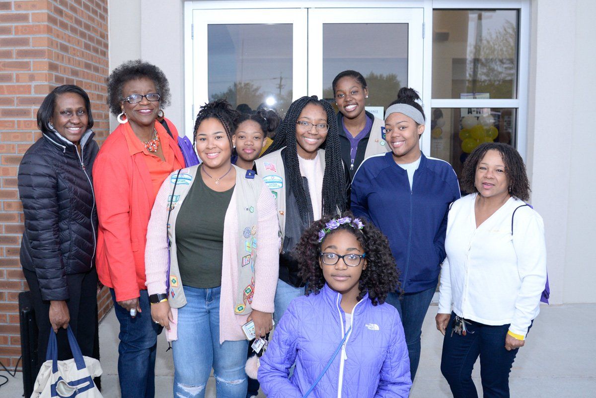 a girl in a purple north face jacket stands in front of a group of women