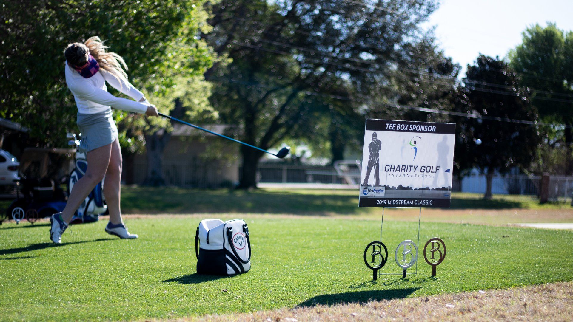 A woman is swinging a golf club on a golf course.