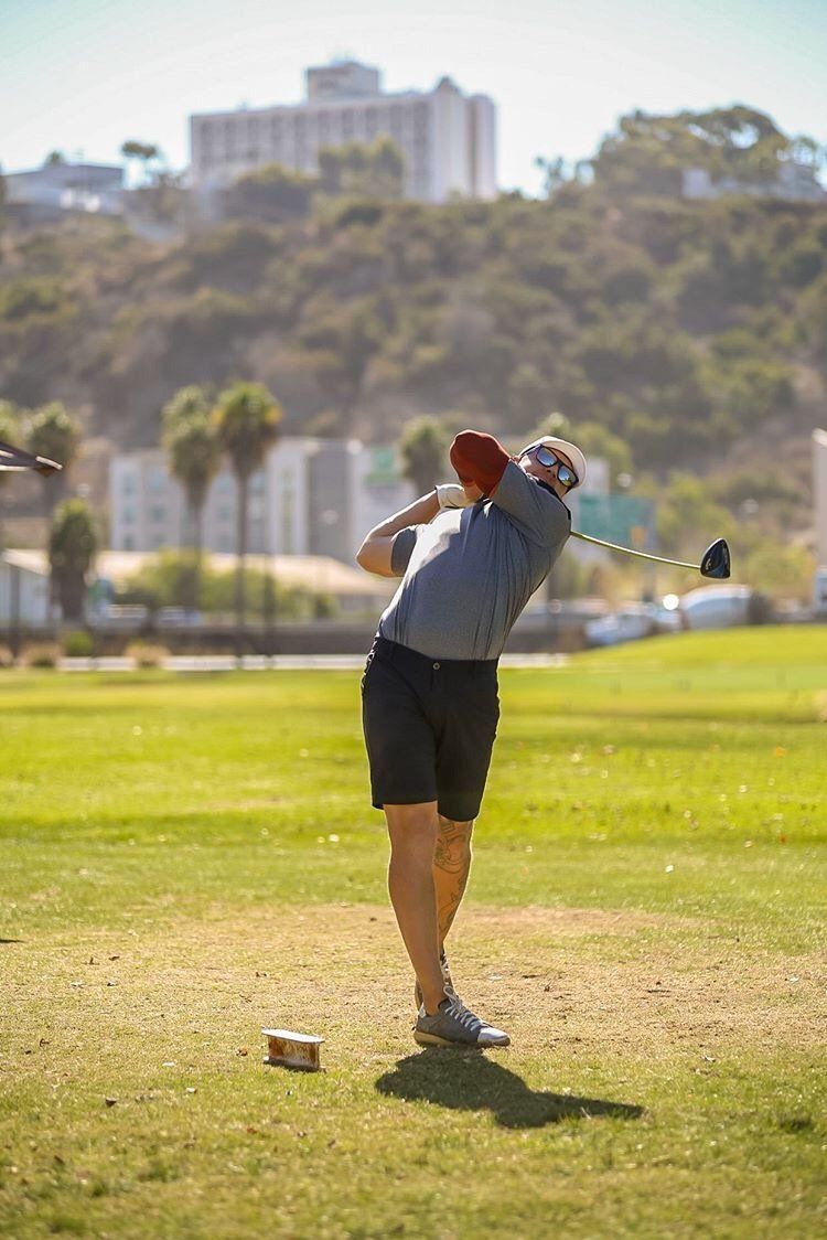 A man is swinging a golf club on a golf course.