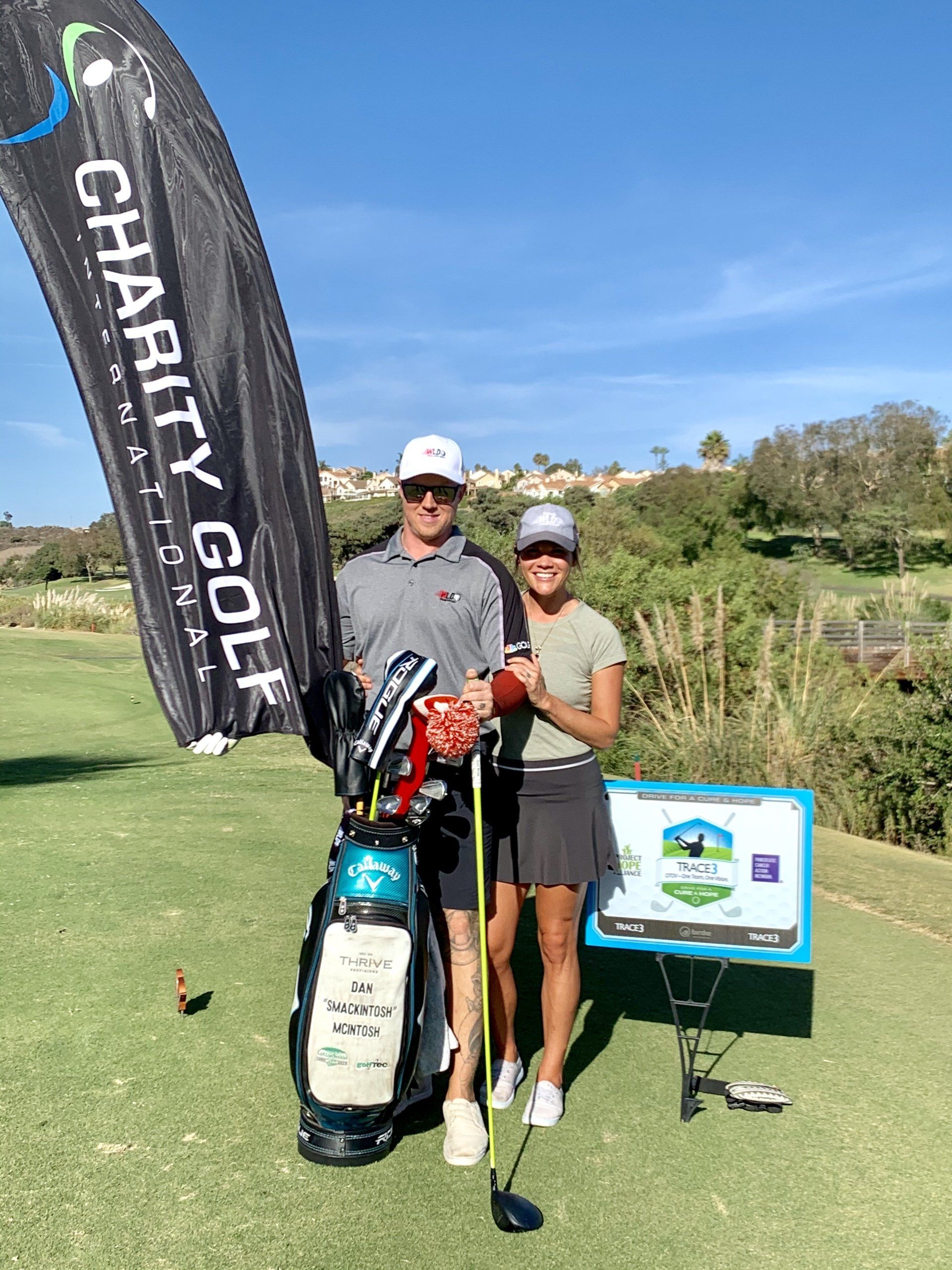 A man and a woman are standing on a golf course holding golf clubs.
