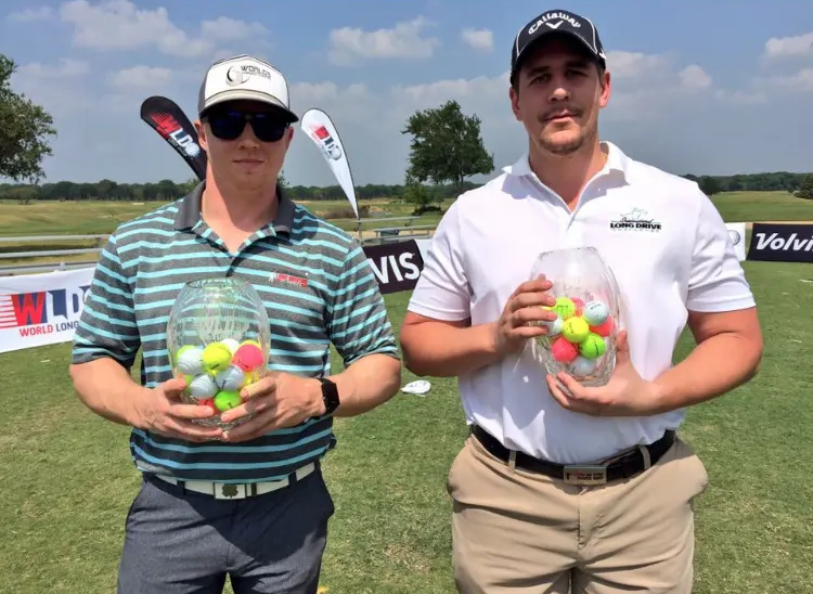 Two men standing on a golf course holding golf balls