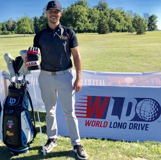 A man is standing in front of a world long drive banner