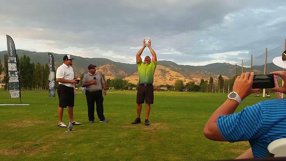 A man is taking a picture of three men standing on a golf course.
