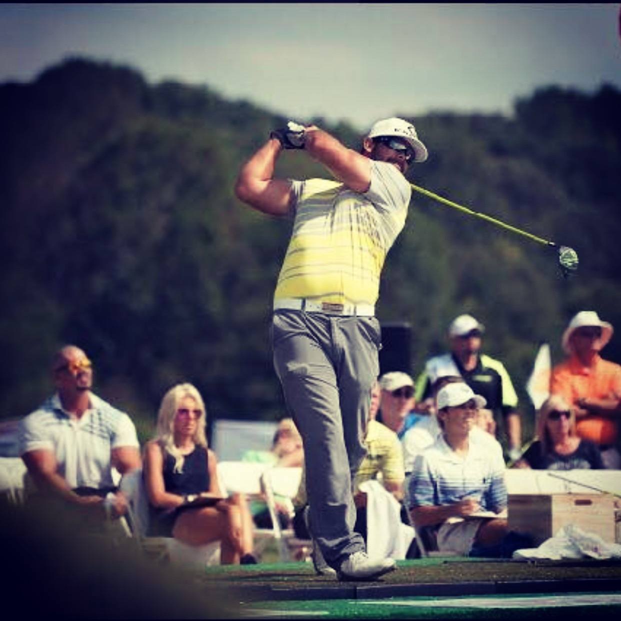 A man is swinging a golf club on a golf course