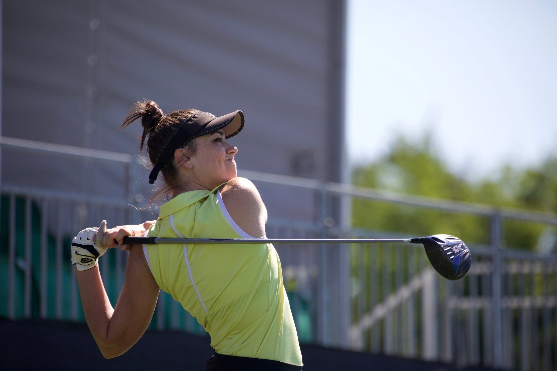 A woman is swinging a golf club on a golf course.