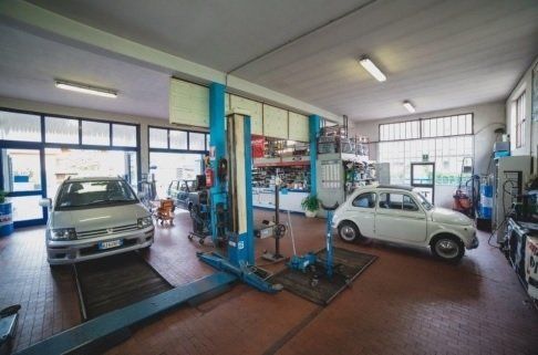 Interno del laboratorio con un'auto in riparazione e un altro già riparato