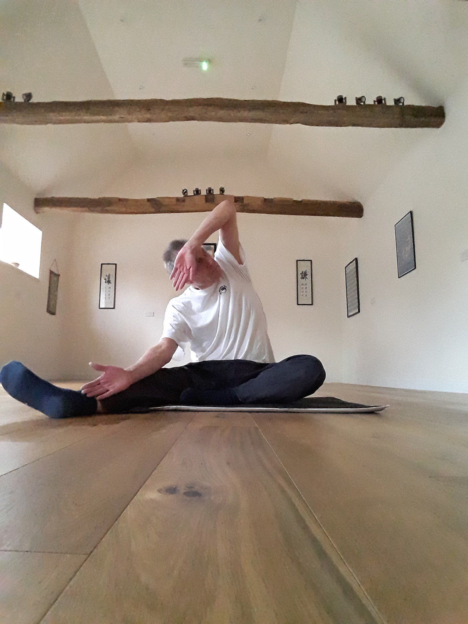 The Balanced Path At The Tai Chi Studio Dave the instructor sitting on the floor, positioned with one leg out and one arm up