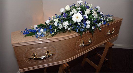 A wooden coffin with a floral tribute laid on top