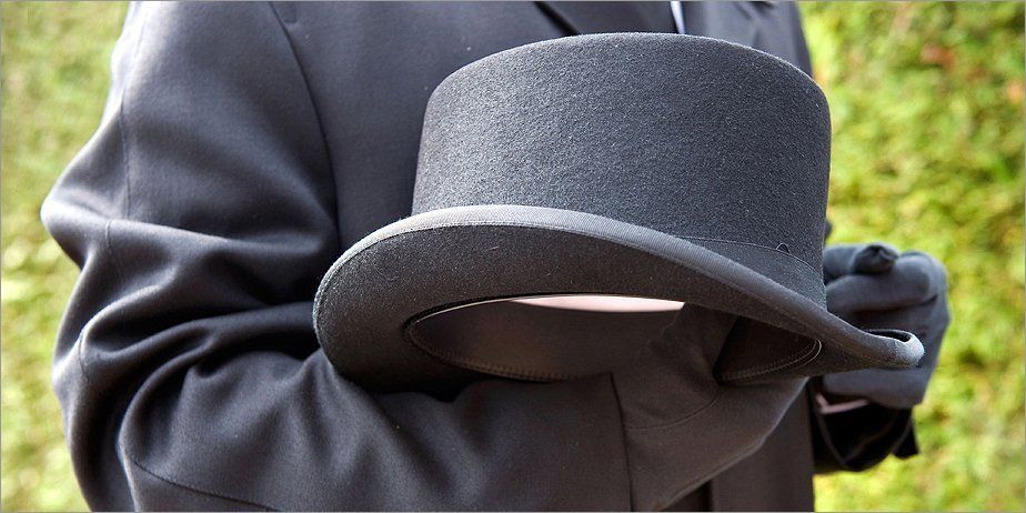 For advice on what to do when someone dies, call 0141 424 0300 A funeral director holding a top hat
