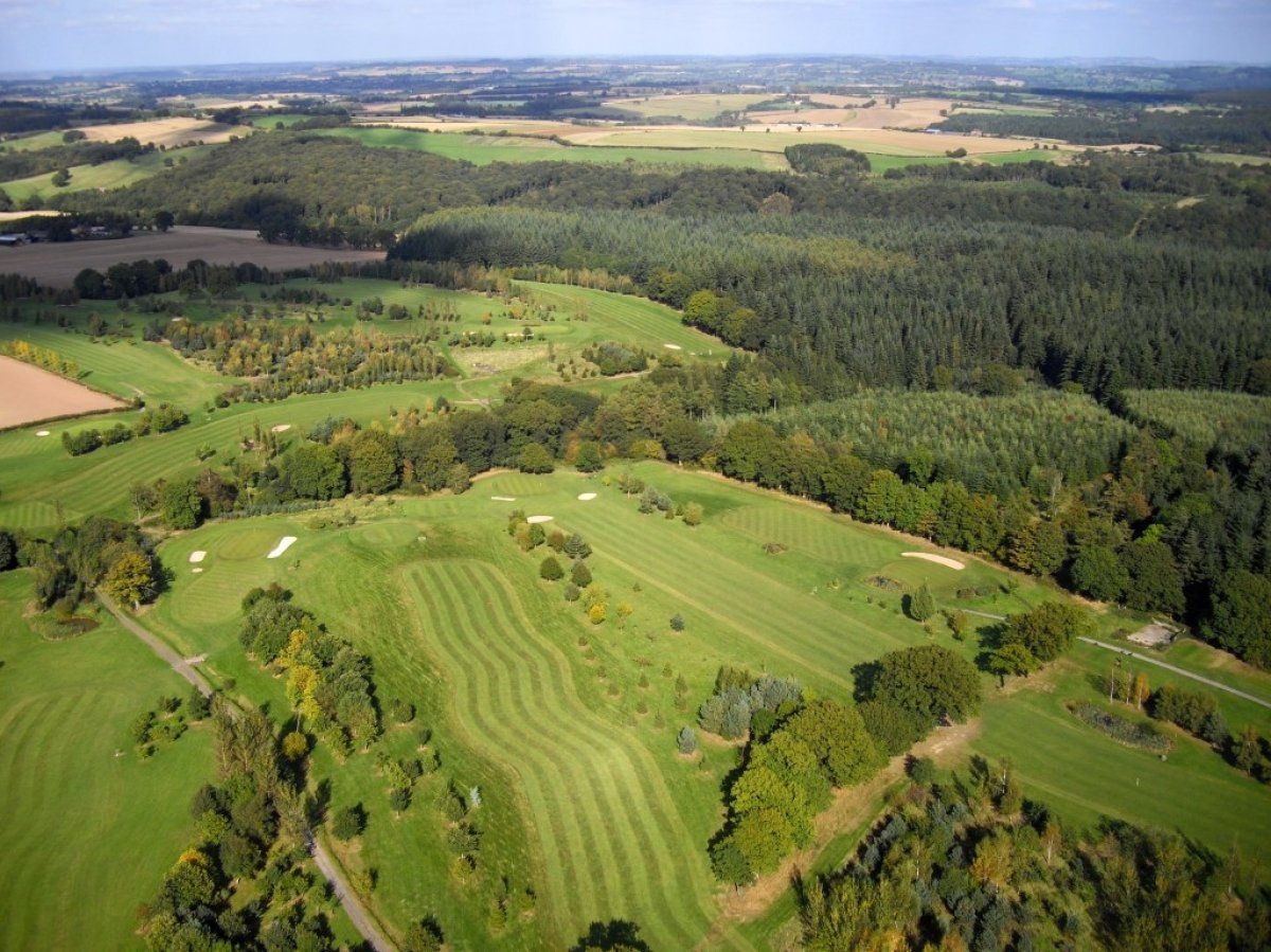 An aerial view of a golf course surrounded by trees and fields.