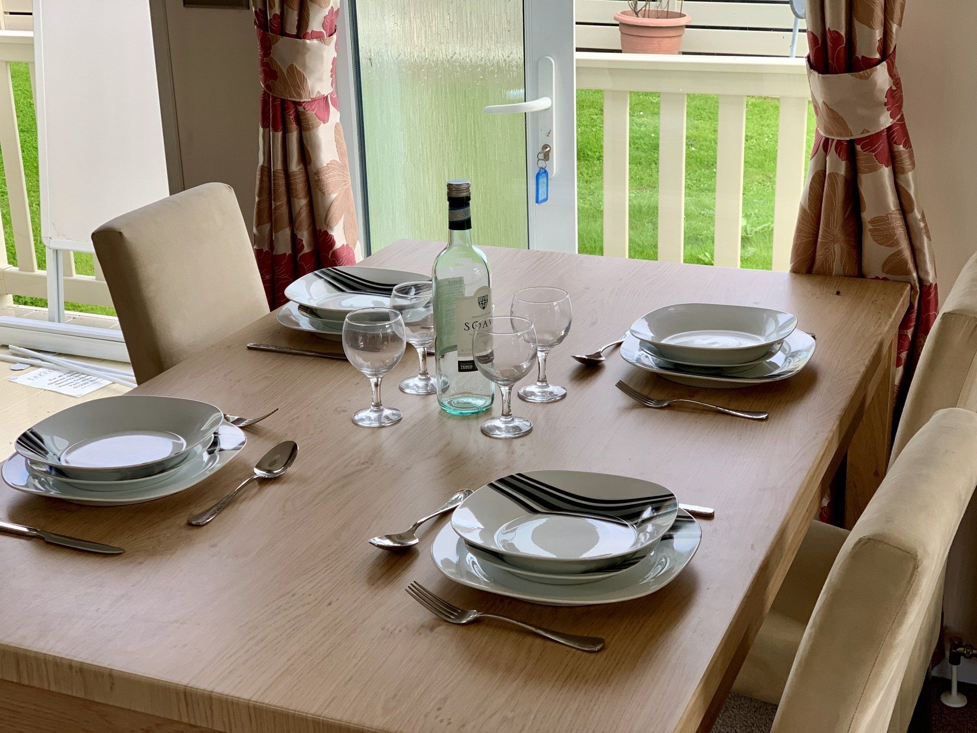 A dining room table with plates , utensils , and a bottle of wine.
