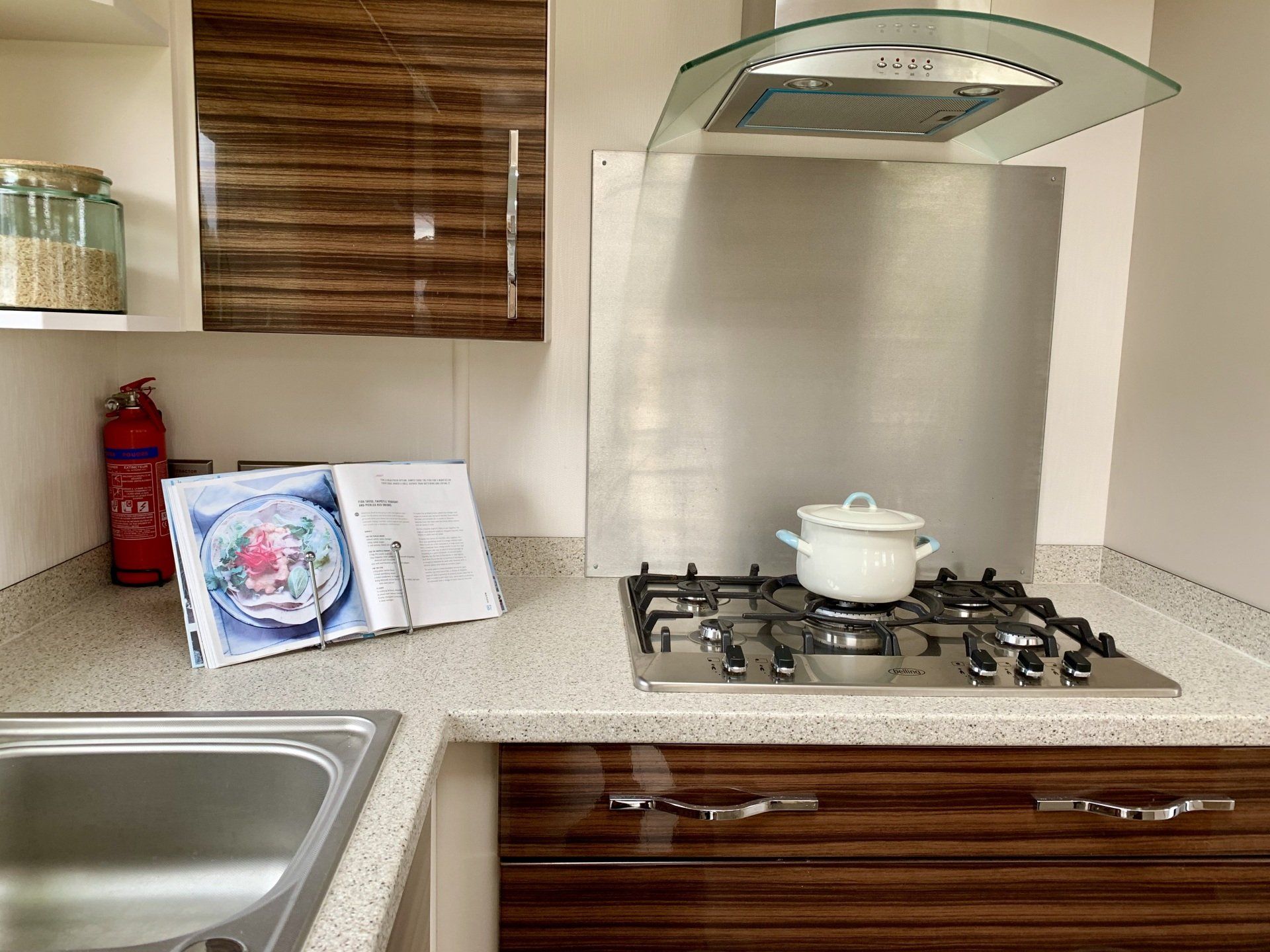 A kitchen with a pot on the stove and a cookbook on the counter.
