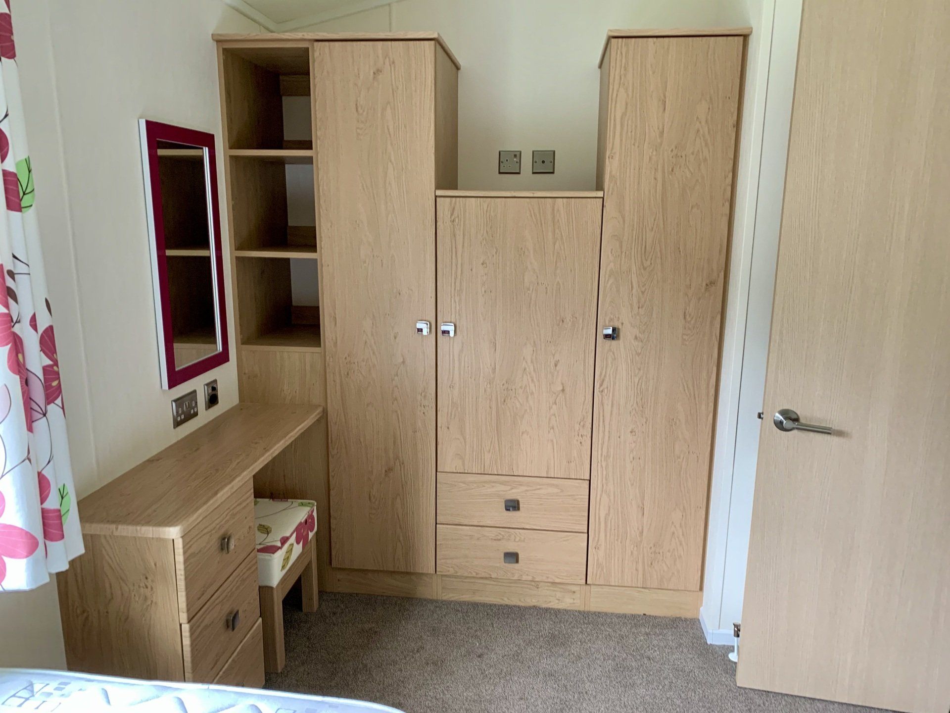 A bedroom with a bed , dresser , wardrobe and mirror.