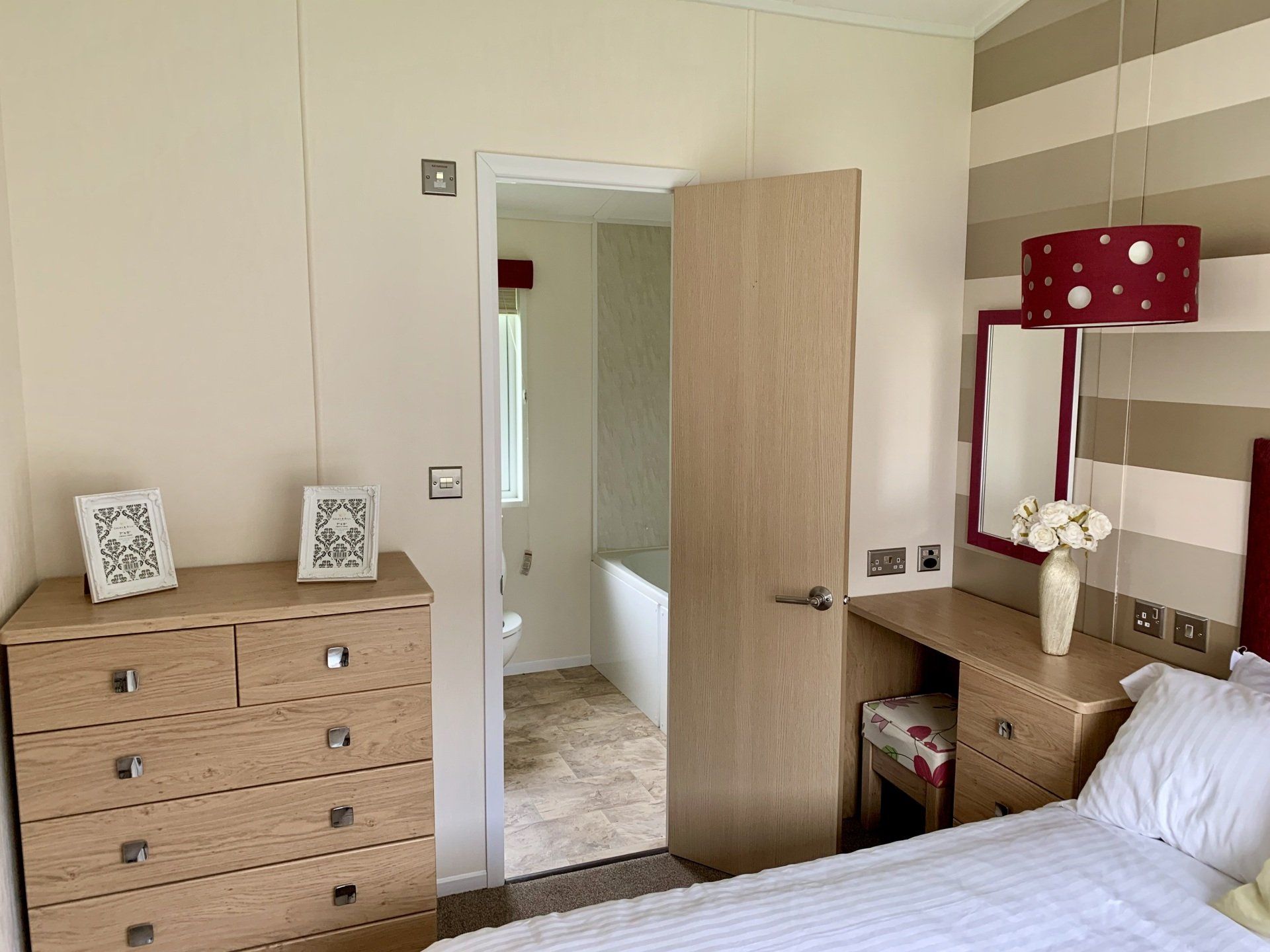 A bedroom with a bed , dresser , mirror and door leading to a bathroom.