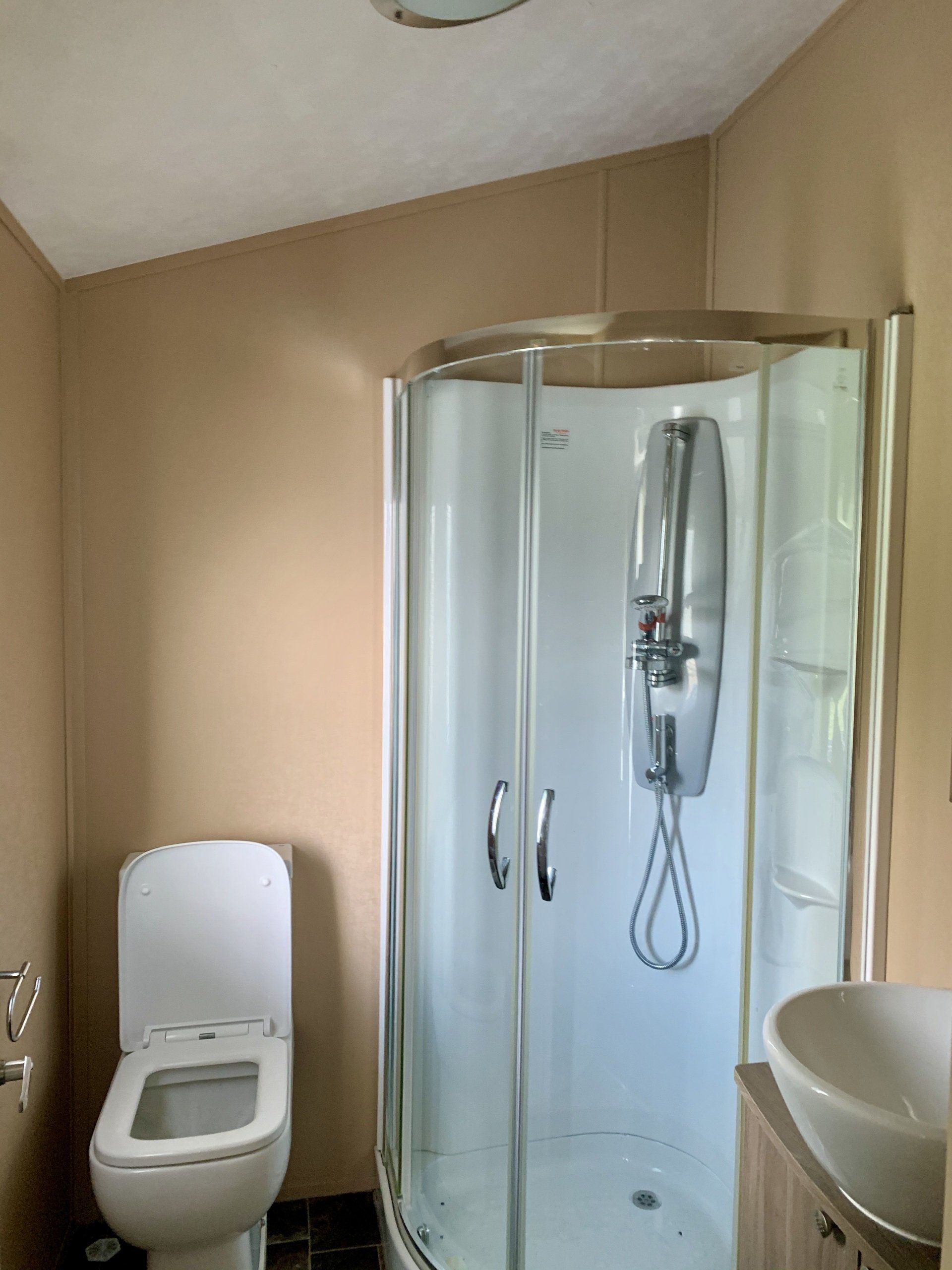 A bathroom with a toilet , sink and shower stall.