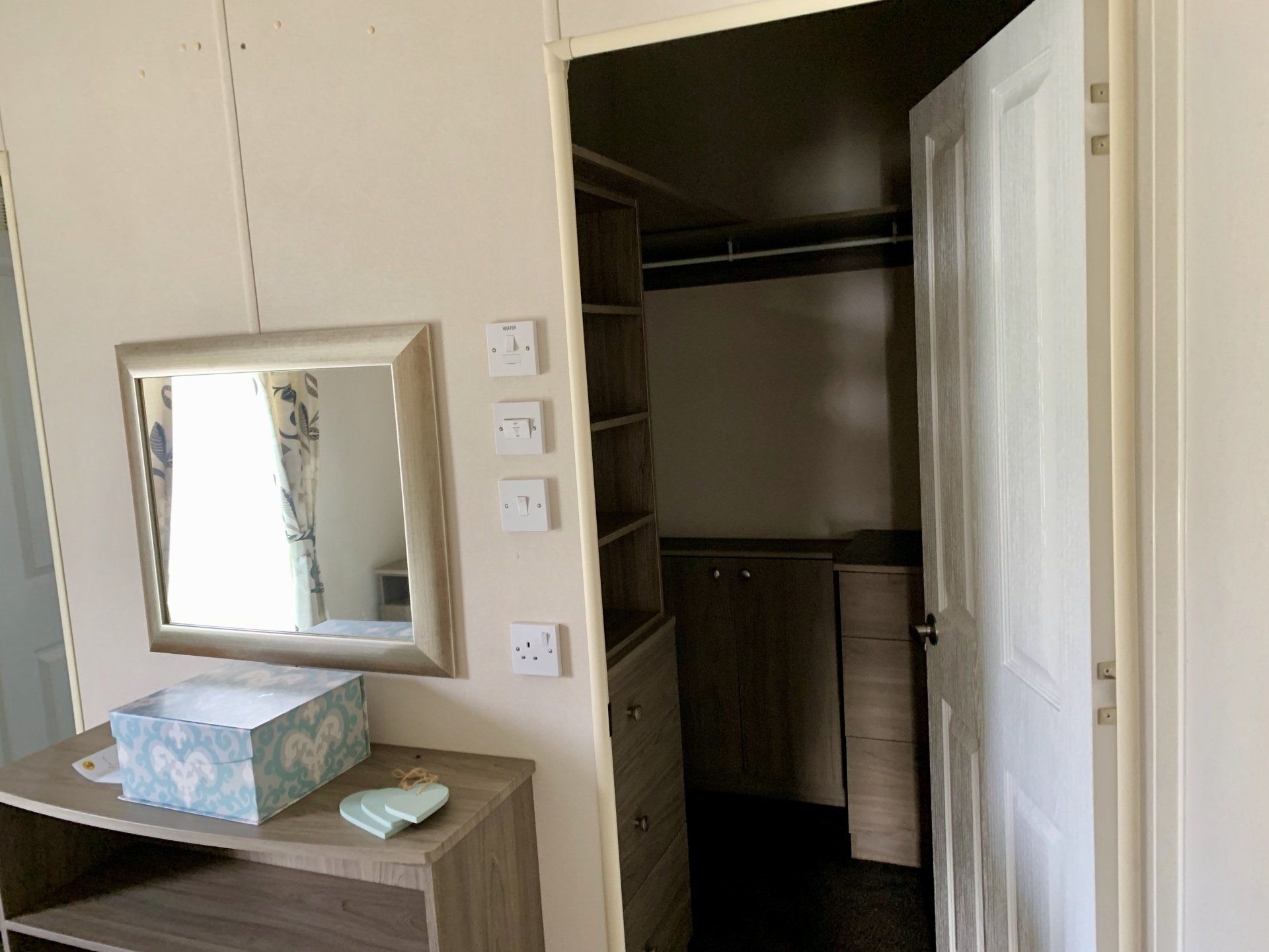 A walk in closet with a mirror and shelves in a room.