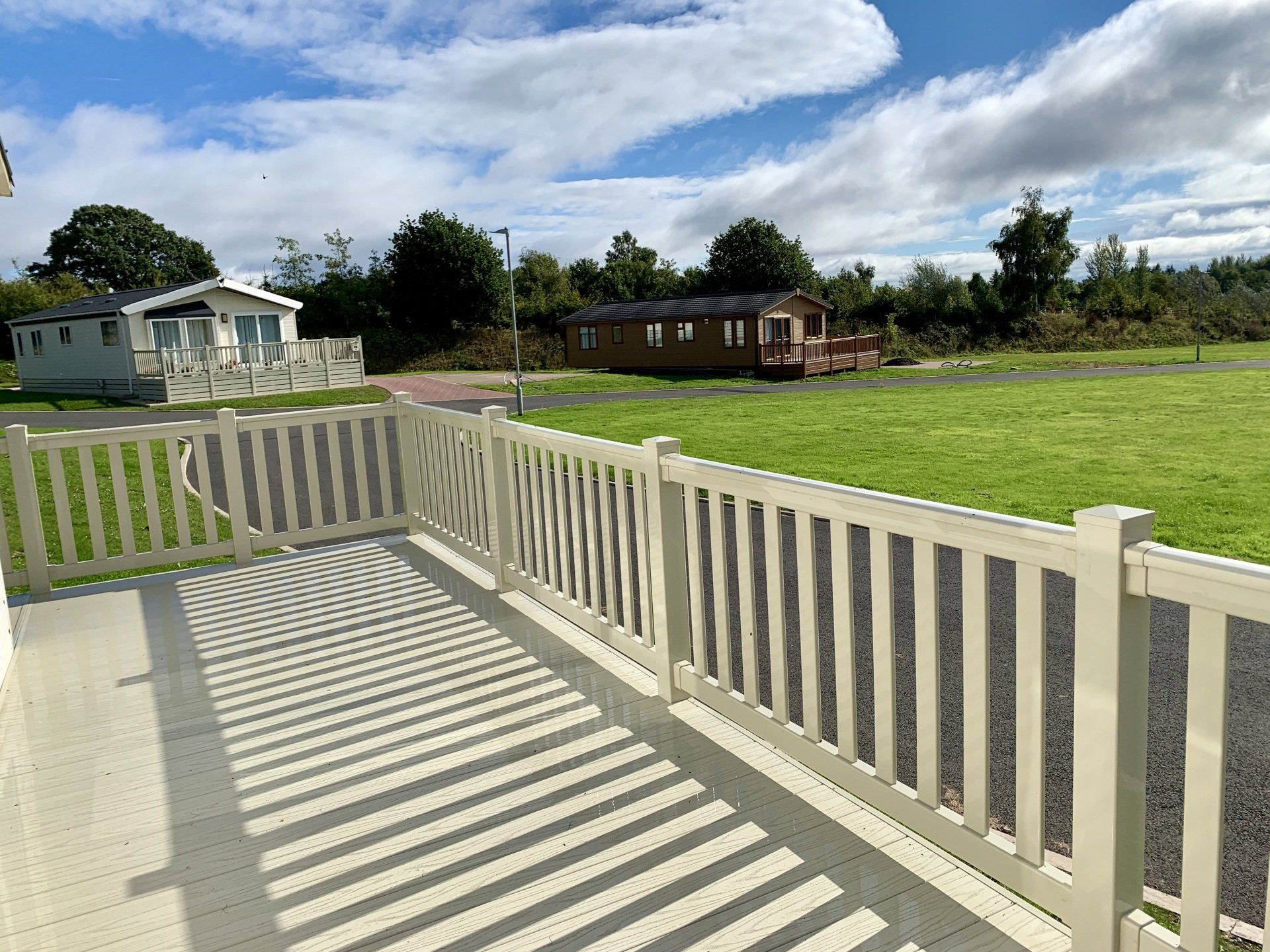 A white fence surrounds a grassy field with a few houses in the background.
