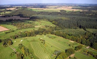 An aerial view of a golf course surrounded by trees and fields.
