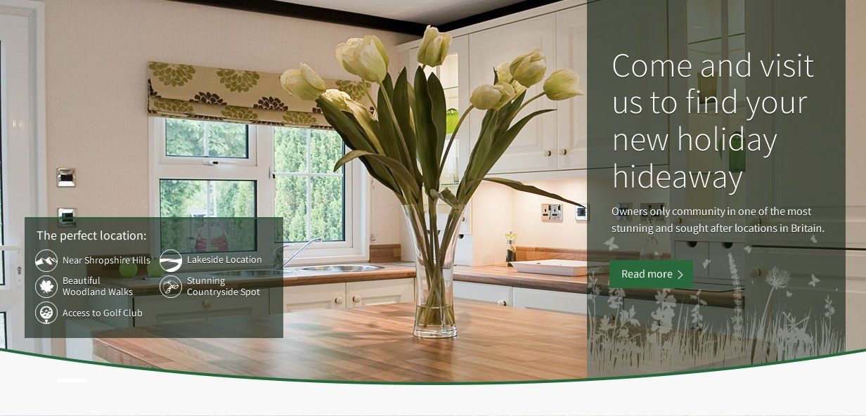 A vase of flowers sits on a wooden table in a kitchen.