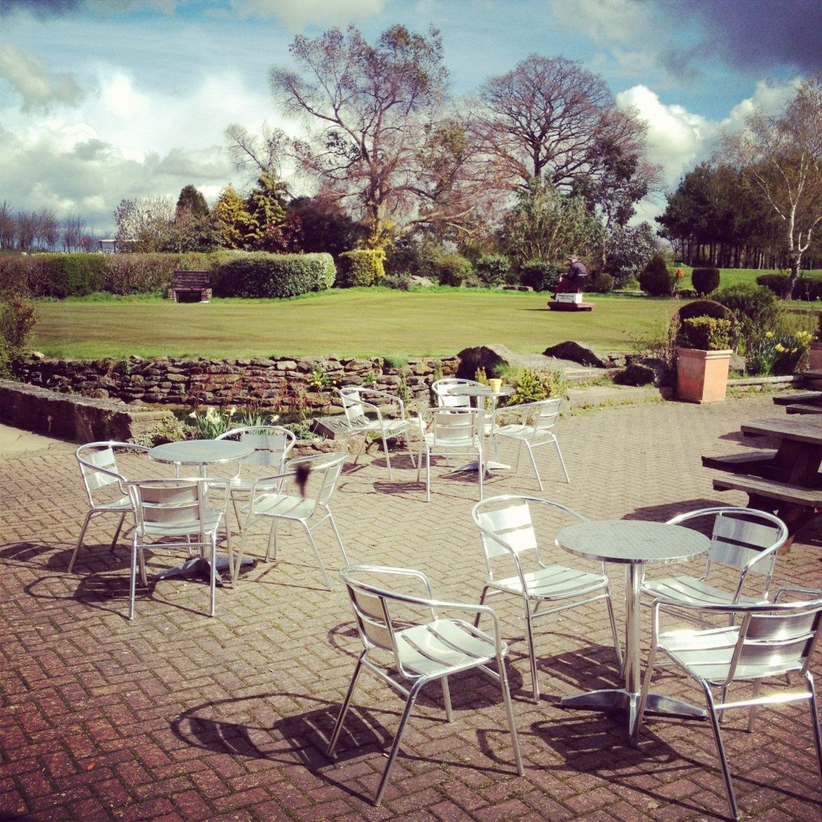 A patio with tables and chairs in front of a grassy field