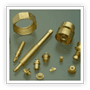 Auf einer Fläche sind verschiedene messingfarbene Metallteile verstreut, darunter ein Ring, ein Zylinder, Stäbe 