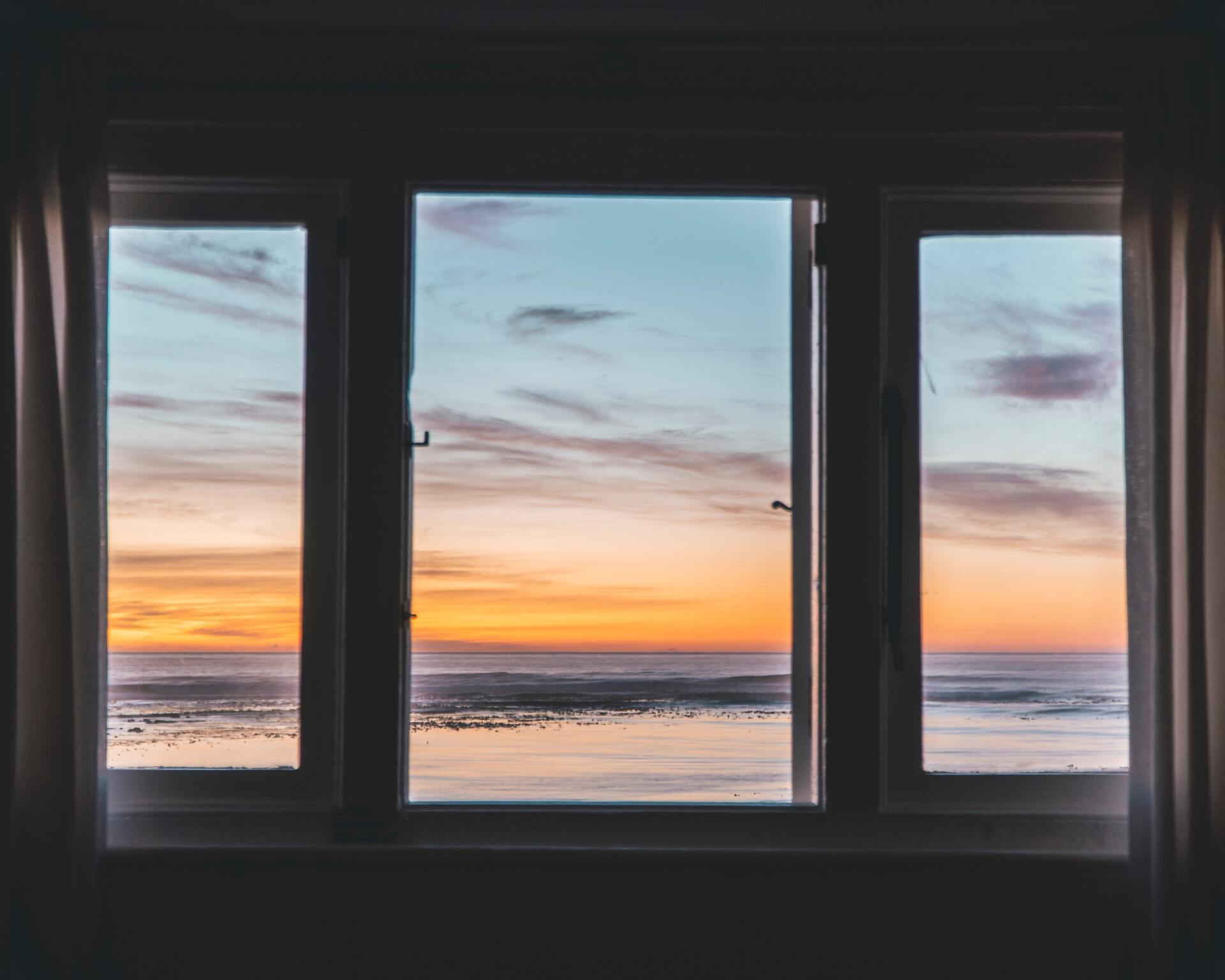 window with a view of the ocean with a sunset
