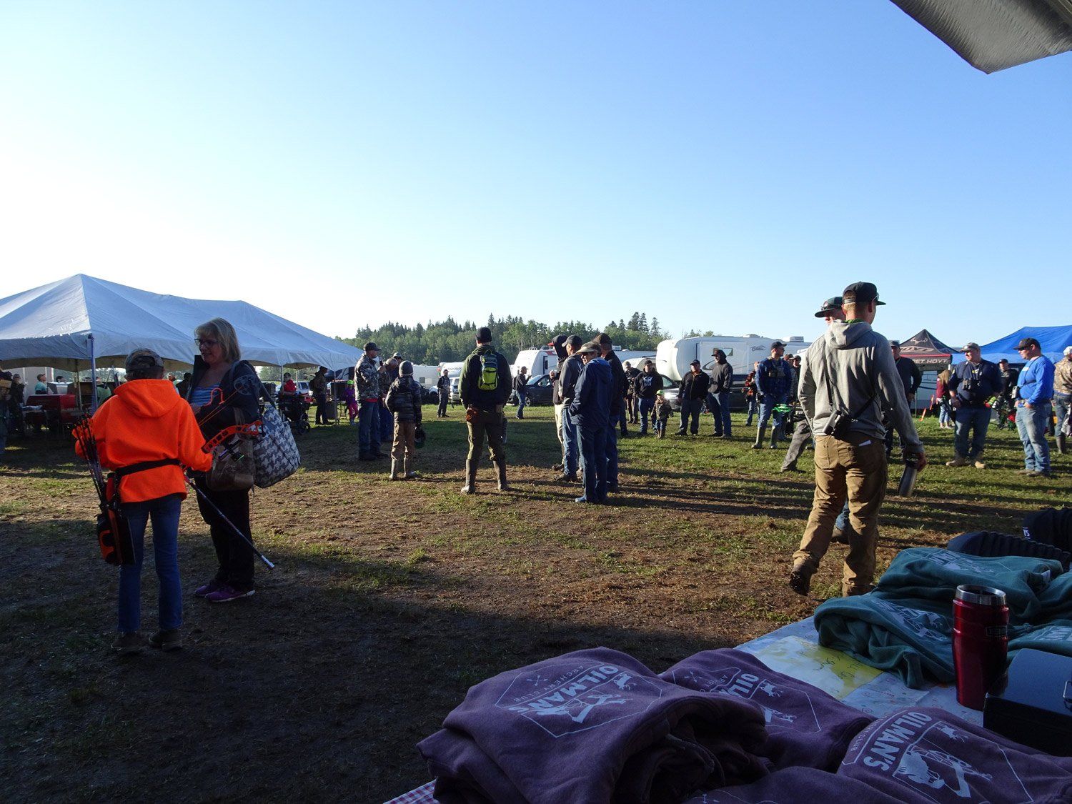 A group of people are gathered in a field with tents