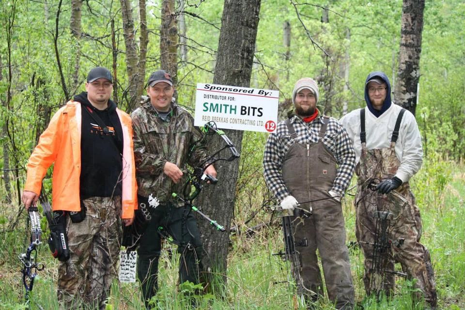 A group of men are standing in the woods holding bows and arrows.