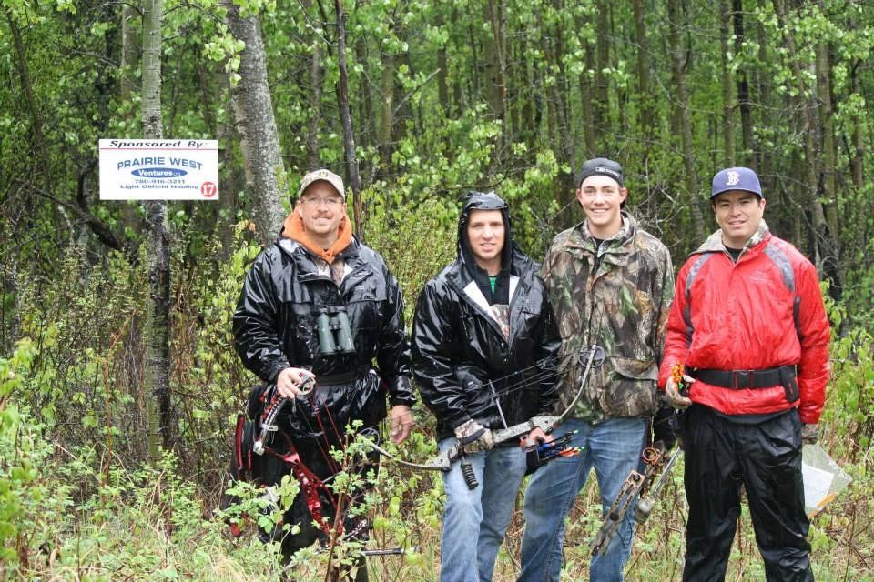 A group of men are standing in a forest with a sign in the background.