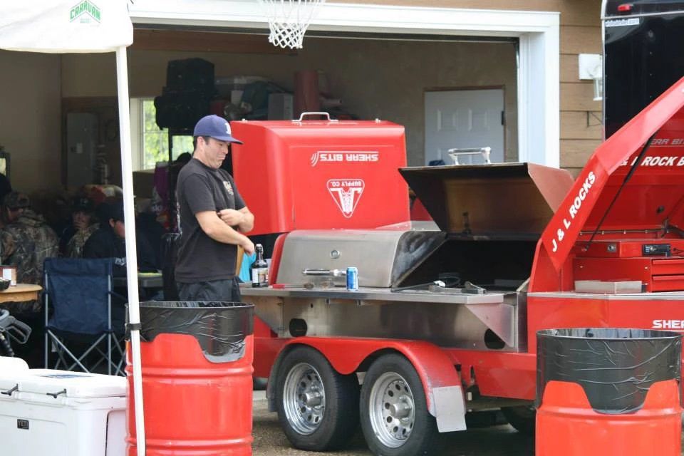 A man is standing next to a red trailer with the hood open