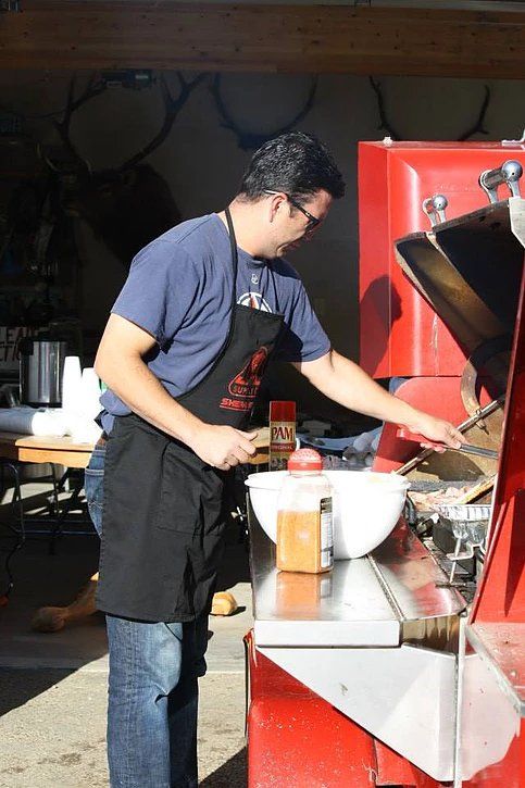 A man in an apron is standing in front of a red machine