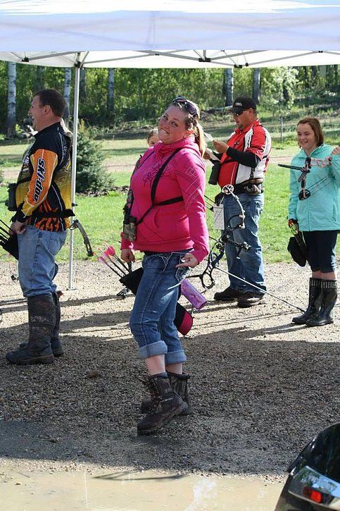 A group of people are standing under a tent holding bows and arrows.