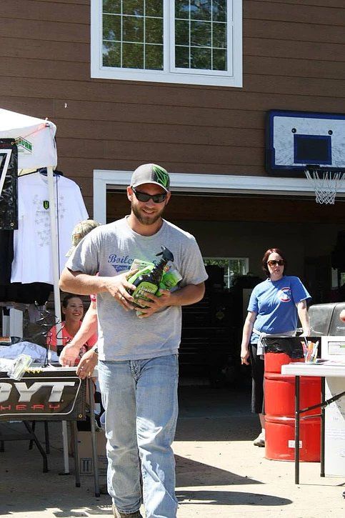 A man is carrying a bottle of beer in front of a garage door.