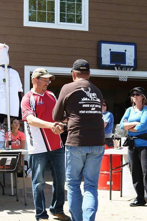 Two men shaking hands in front of a basketball hoop